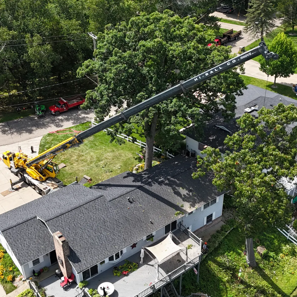 Crane lifting tree branches during an emergency tree removal near a residential home in Battle Creek, MI.
